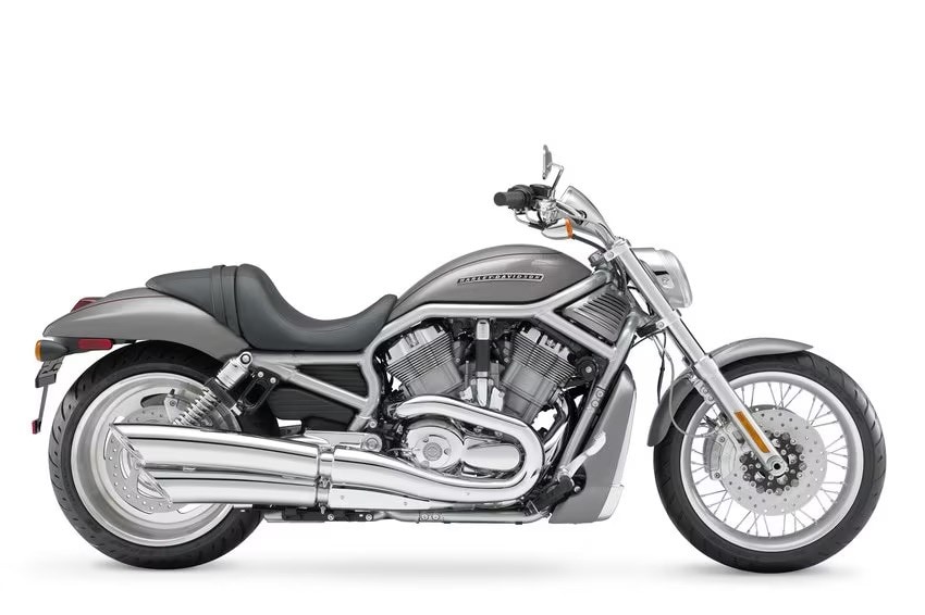 <div class='descrGalleryTitle'>V-Rod</div><div class='descrGalleryText'><p>Siamo nel 2001, il Millennium Bug è alle spalle, il mondo sembra lanciato a tutta velocità verso nuovi traguardi e <b>Harley decide di dare finalmente alla luce il chiacchierato V-twin a liquido </b>di cui si vocifera da anni. L’obiettivo di una azienda ormai di nuovo in piena salute è quello di prendere di petto la concorrenza giapponese ed europea in fatto di “muscle bike”. <b>La V-Rod definisce una nuova estetica in stile “drag race”</b>, con la forma allungata, la forcella inclinata di 34° e l’enorme gomma posteriore, che avrà un impatto duraturo, ma soprattutto introduce un motore completamente inedito, sviluppato in <b>collaborazione con Porsche</b>:<b> è un V di 60° con imbiellaggio tradizionale, contralbero, raffreddamento a liquido, </b>distribuzione bialbero a camme in testa, iniezione elettronica, 115 CV e un’erogazione autenticamente sportiva. Si tratta di un motore concettualmente moderno, <b>non per nulla battezzato “Revolution”. </b>Con il serbatoio posto sotto la sella, il telaio idroformato e i freni Brembo, la V-Rod aveva personalità da vendere e buoni punti di forza sul dritto, anche se <b>il peso di quasi 300 kg e l’interasse di 1.700 mm </b>ne limitavano decisamente la maneggevolezza. Divise gli harleysti in due: una parte minoritaria che la apprezzò subito, e <b>una maggioranza che la snobbò</b> convinta che le H-D dovessero essere solo V 45°, con distribuzione ad aste e bilancieri e raffreddate ad aria. La V-Rod ebbe quindi un successo modesto, ma<b> rimase comunque in produzione fino al 2017</b>&nbsp;in diverse versioni, anche di grande fascino come la Night Rod. Il suo motore non sbarcò su nessun’altra piattaforma, ma <b>fu ripreso in piccolo con la serie Street del 2013: </b>un altro fiasco clamoroso.</p>
</div>